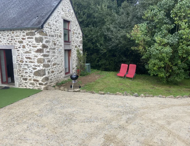 Jardin du gîte en Bretagne avec deux transats rouges installés près des arbres, offrant un espace calme et reposant. »